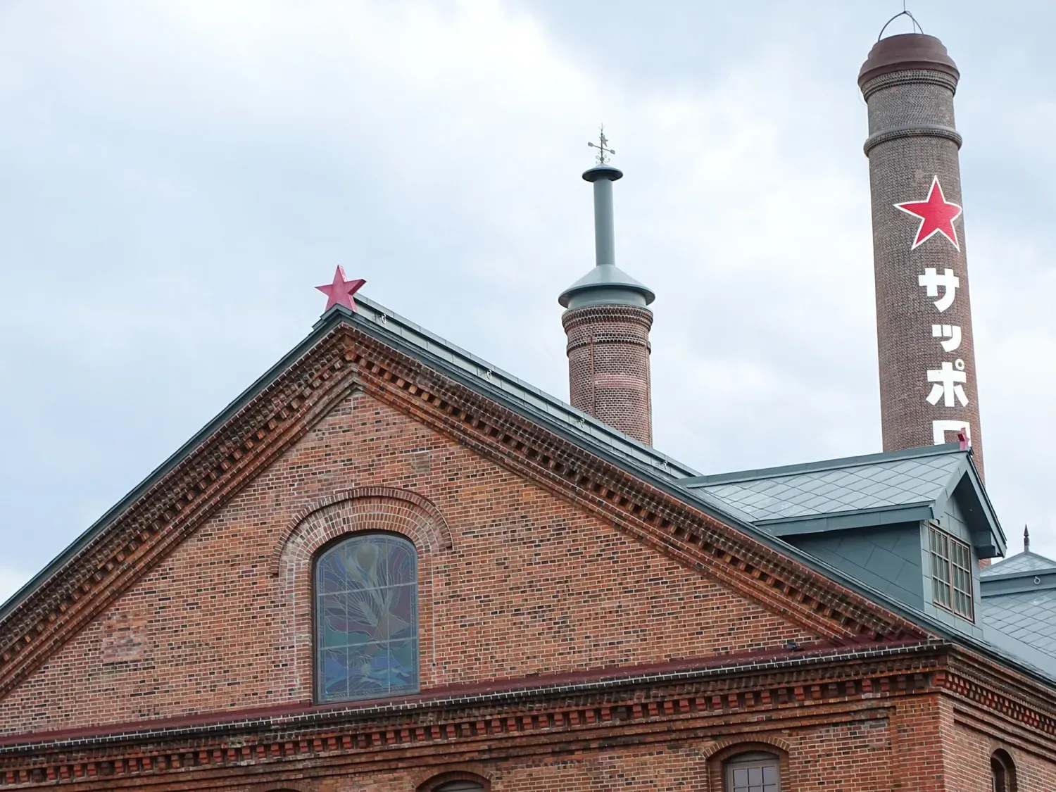 The gabled red-brick front of the Sapporo Beer Museum, with a tall brick chimney marked with a red star