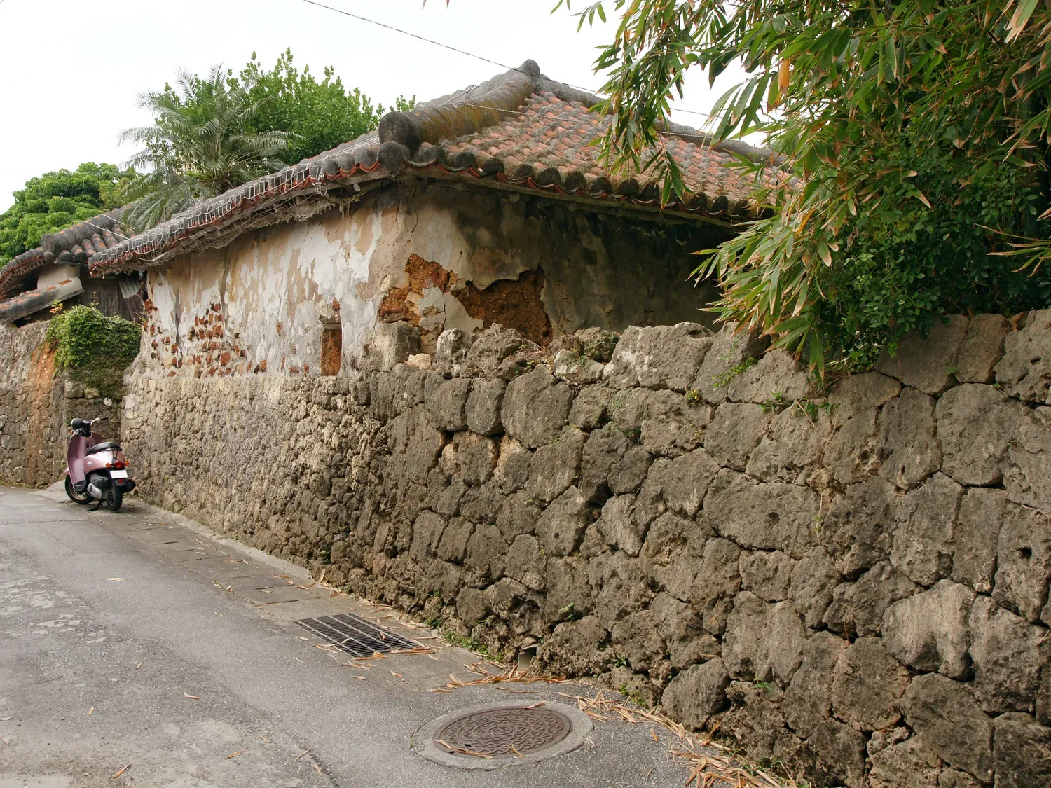 The Arakaki house in Tsuboya: a red-tiled roof above a wall of rough limestone blocks, on a quiet lane