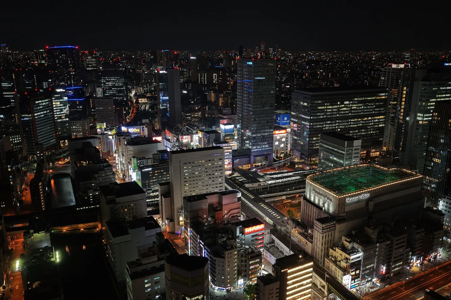 Akihabara Station and the buildings of the electric town glowing at night, seen from high above