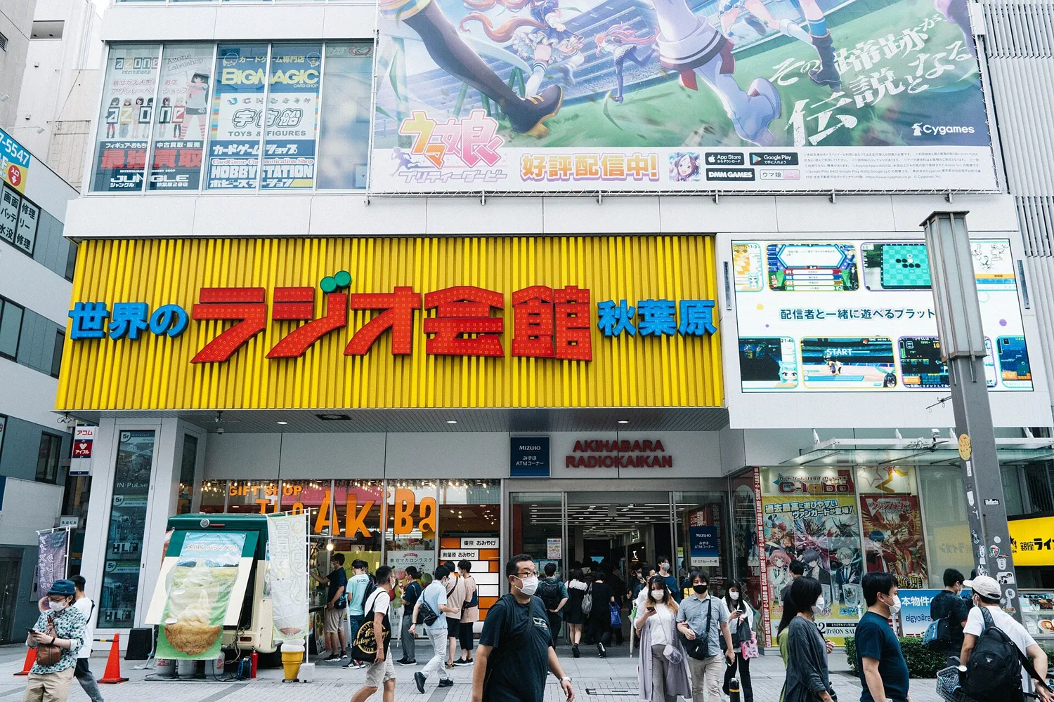 The front of Akihabara Radio Kaikan with its yellow sign reading Sekai no Radio Kaikan, Akihabara, and shoppers on the pavement below
