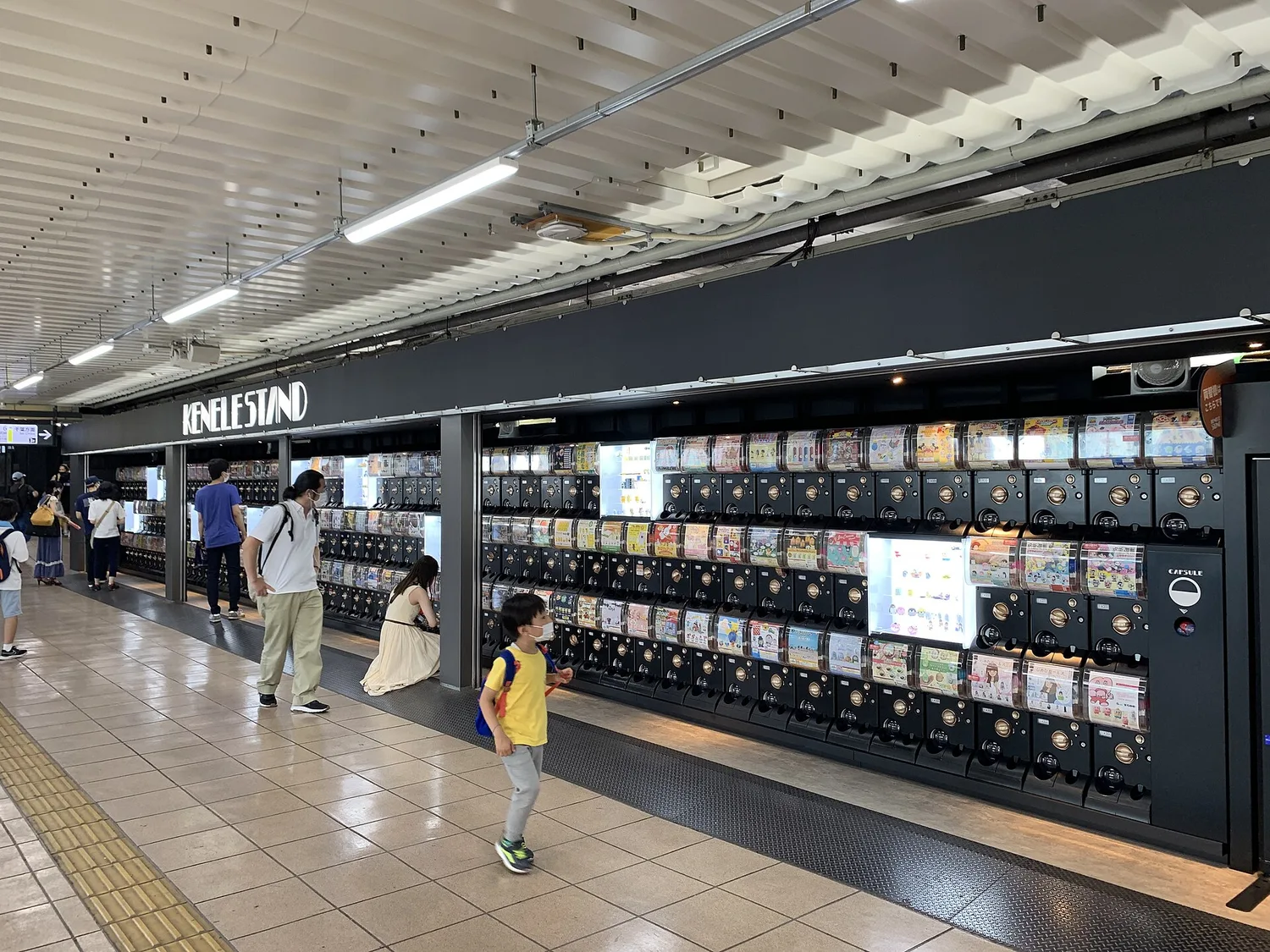 A long wall of capsule toy machines at a shop on a JR Akihabara Station platform