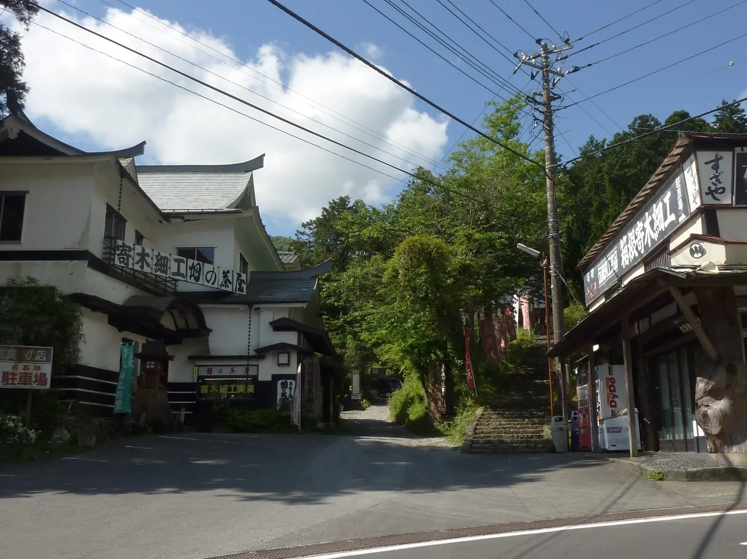 A quiet village street with old two-story wooden houses and forested hills behind