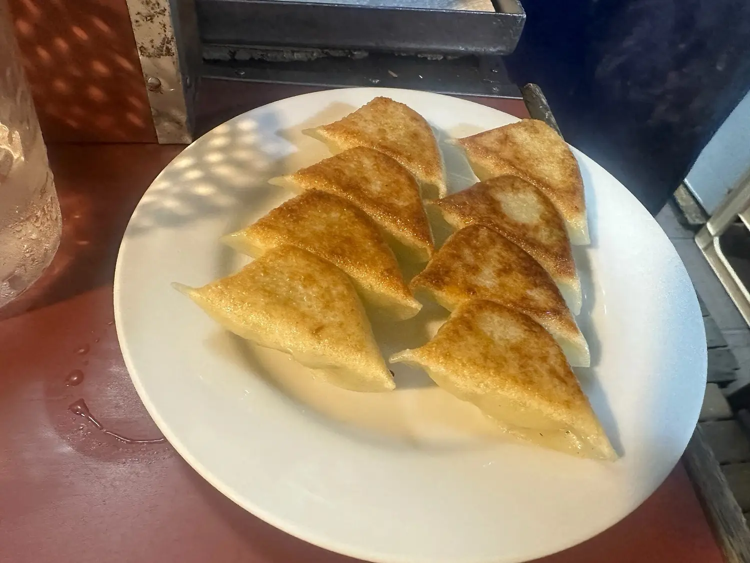 A plate of pan-fried gyoza on a red yatai counter at night