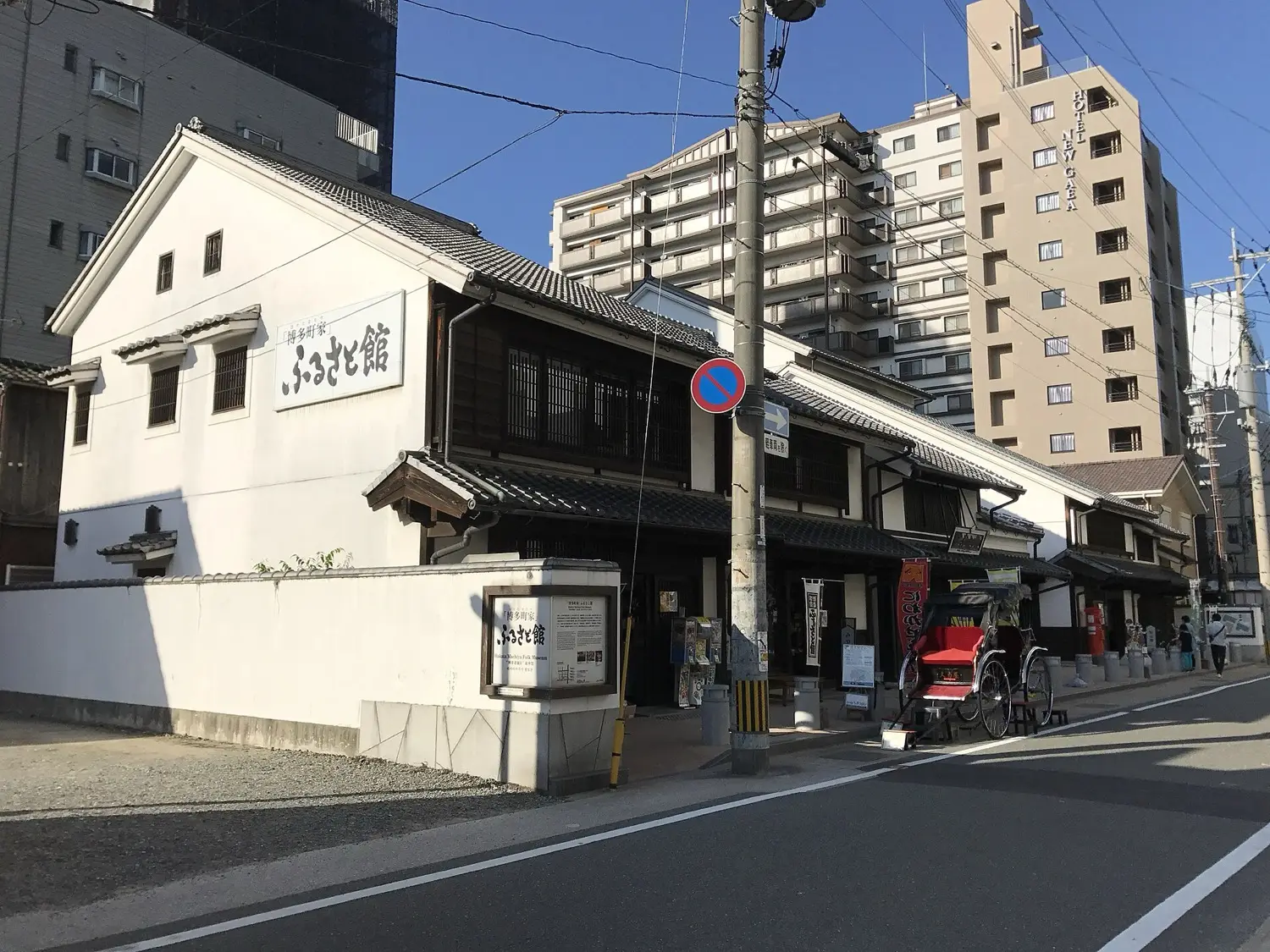 A white-walled two-storey building with a dark tiled roof on a street corner