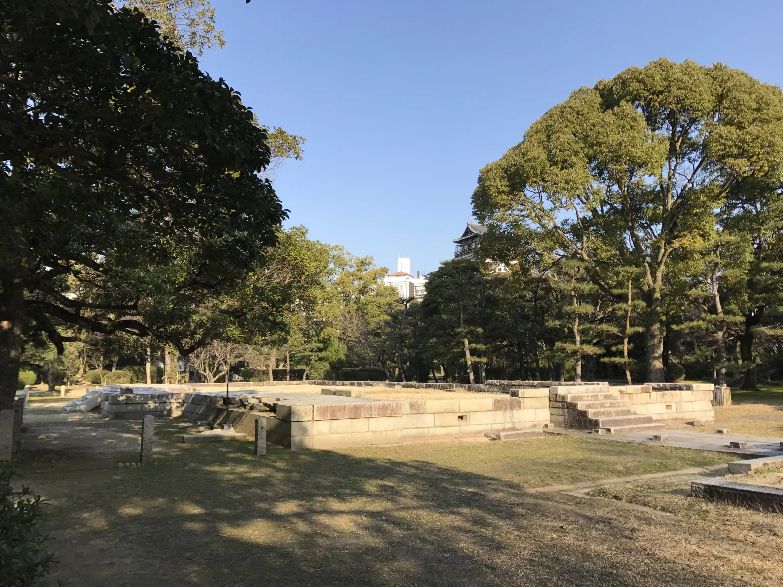 Low stone foundations in a grassy clearing among trees