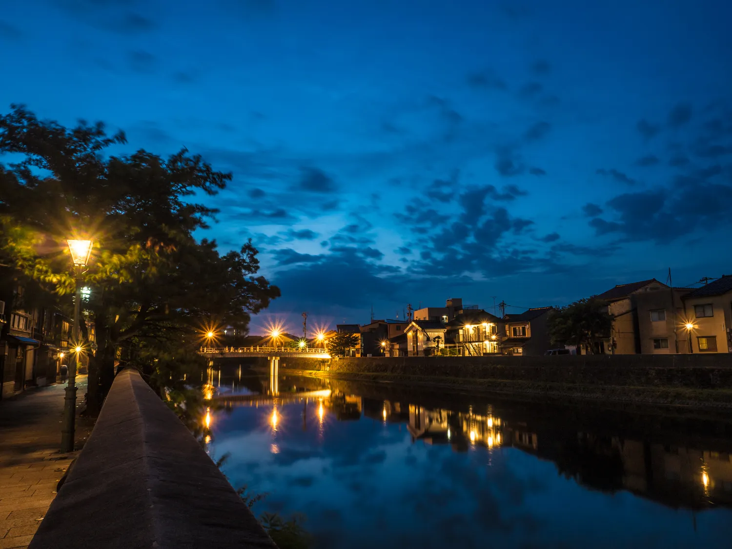 The Asano River at dusk, street lamps and a bridge reflected in the water, Kazuemachi on the bank