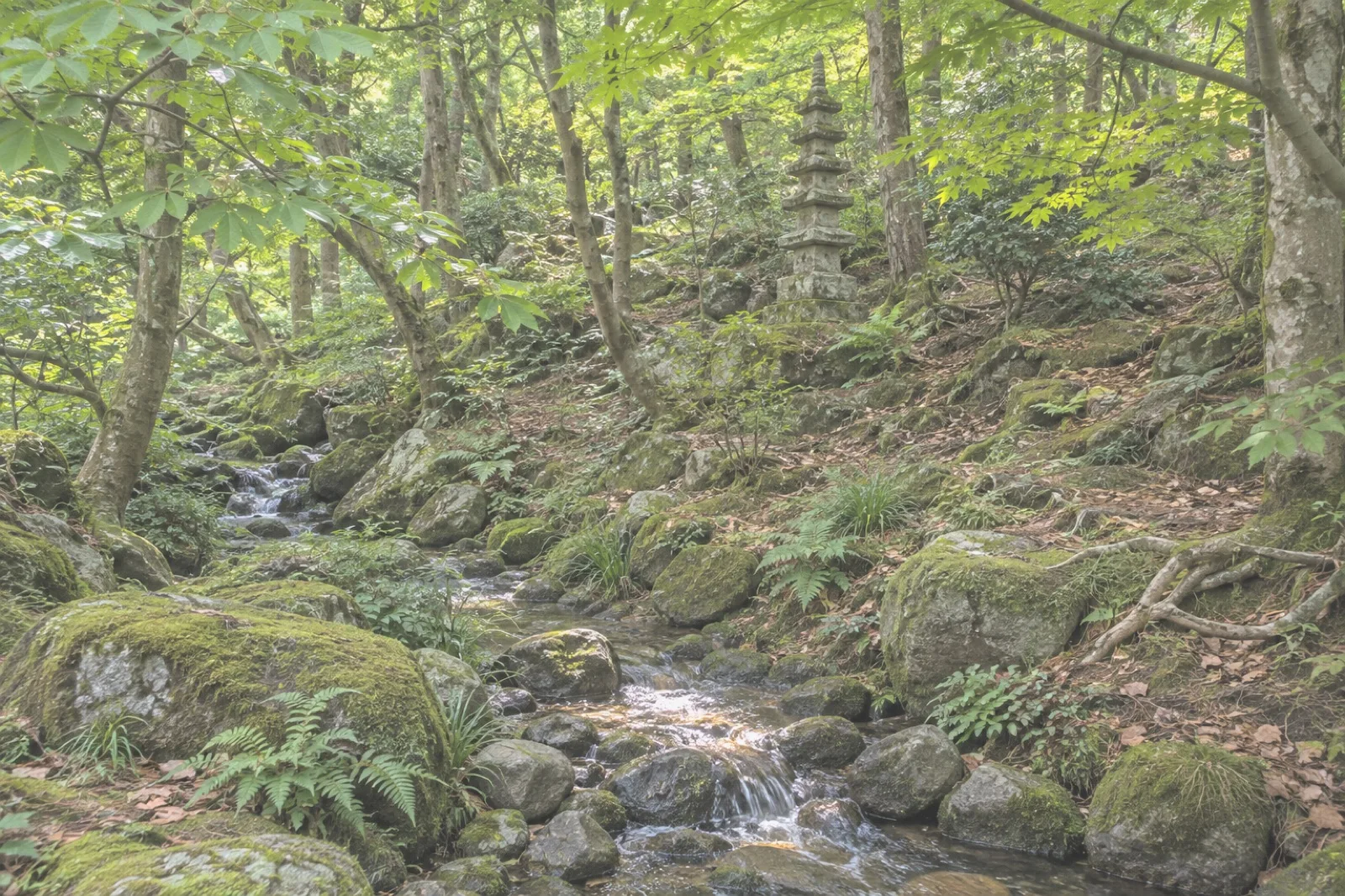 A narrow stream running under trees, with a stone pagoda on the slope