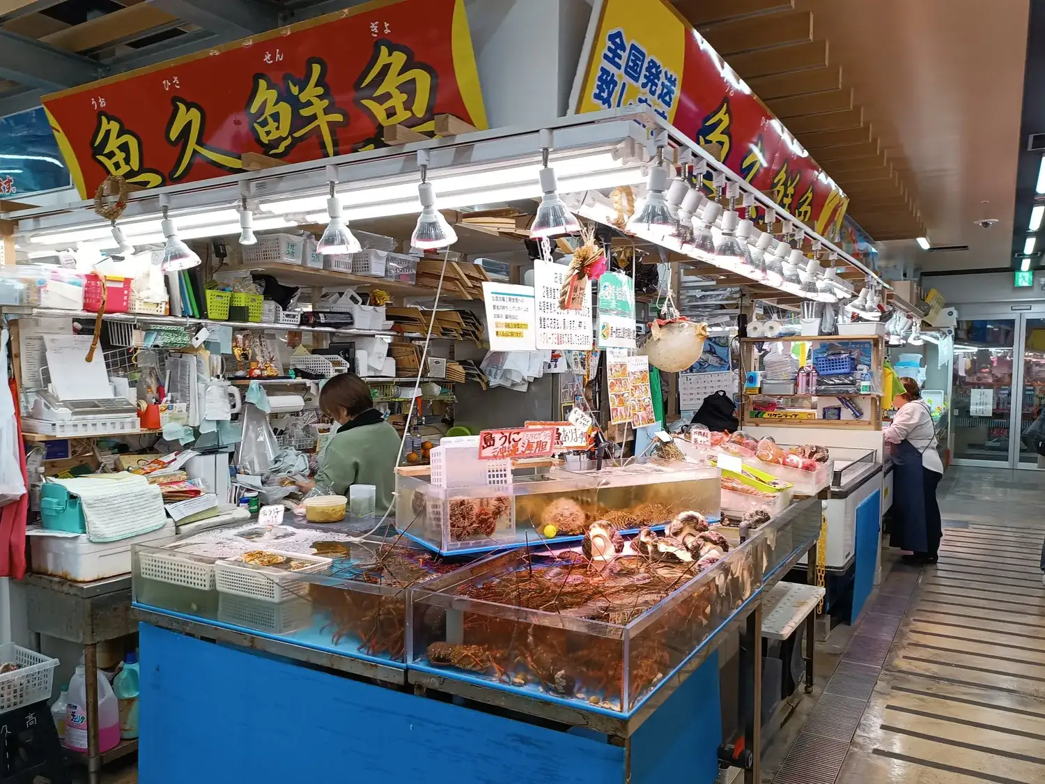 A fishmonger's counter inside the market, with a red sign above and an aisle running past other stalls