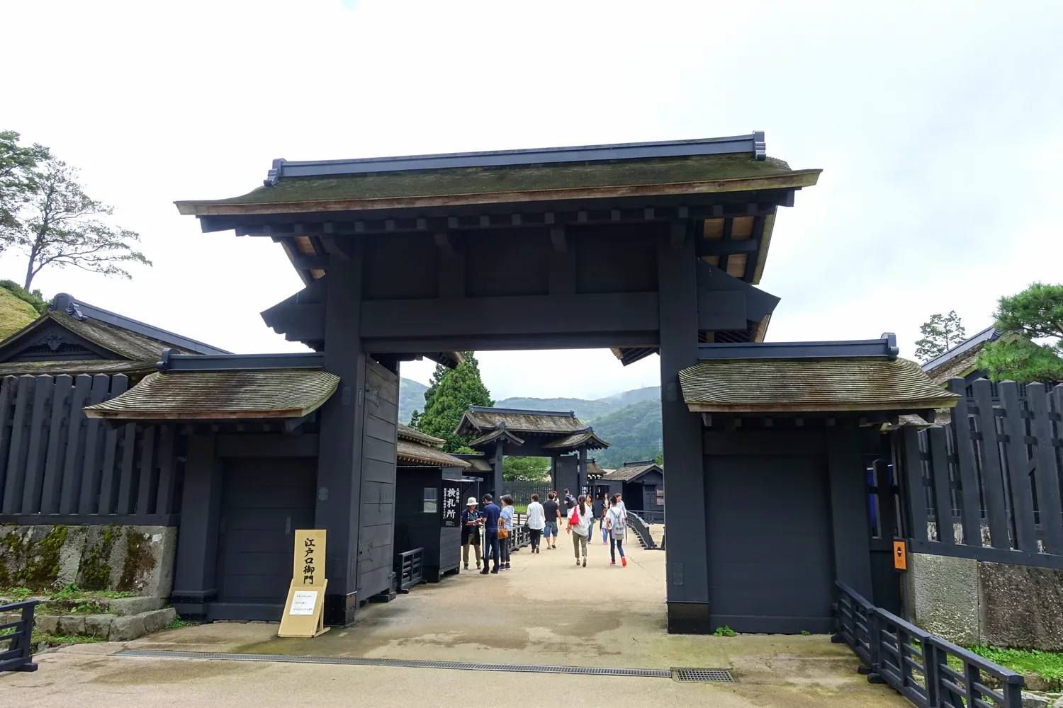 A dark wooden gate of an Edo-period checkpoint, with visitors walking through