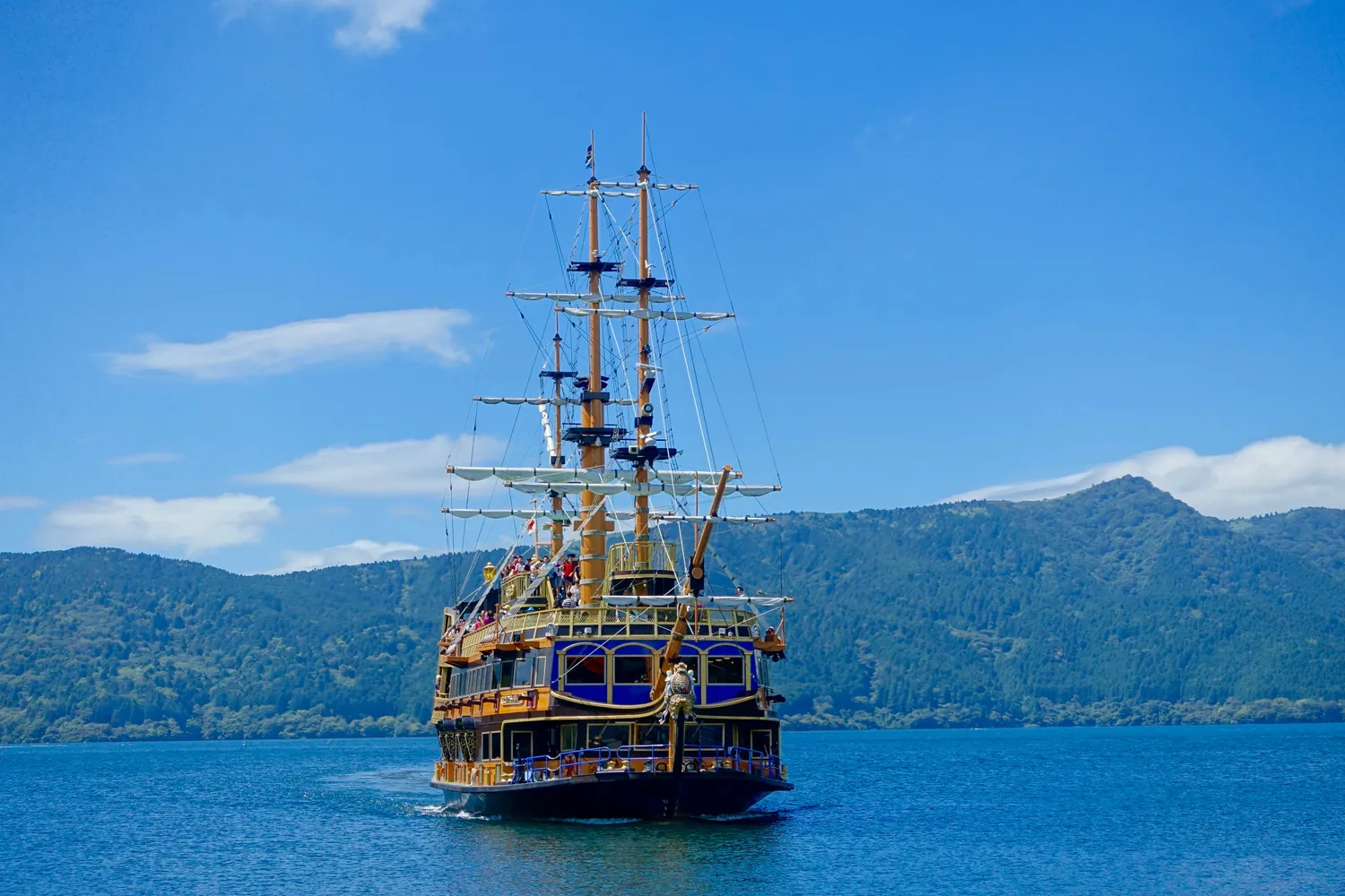 A replica sailing warship with tall masts on a blue lake