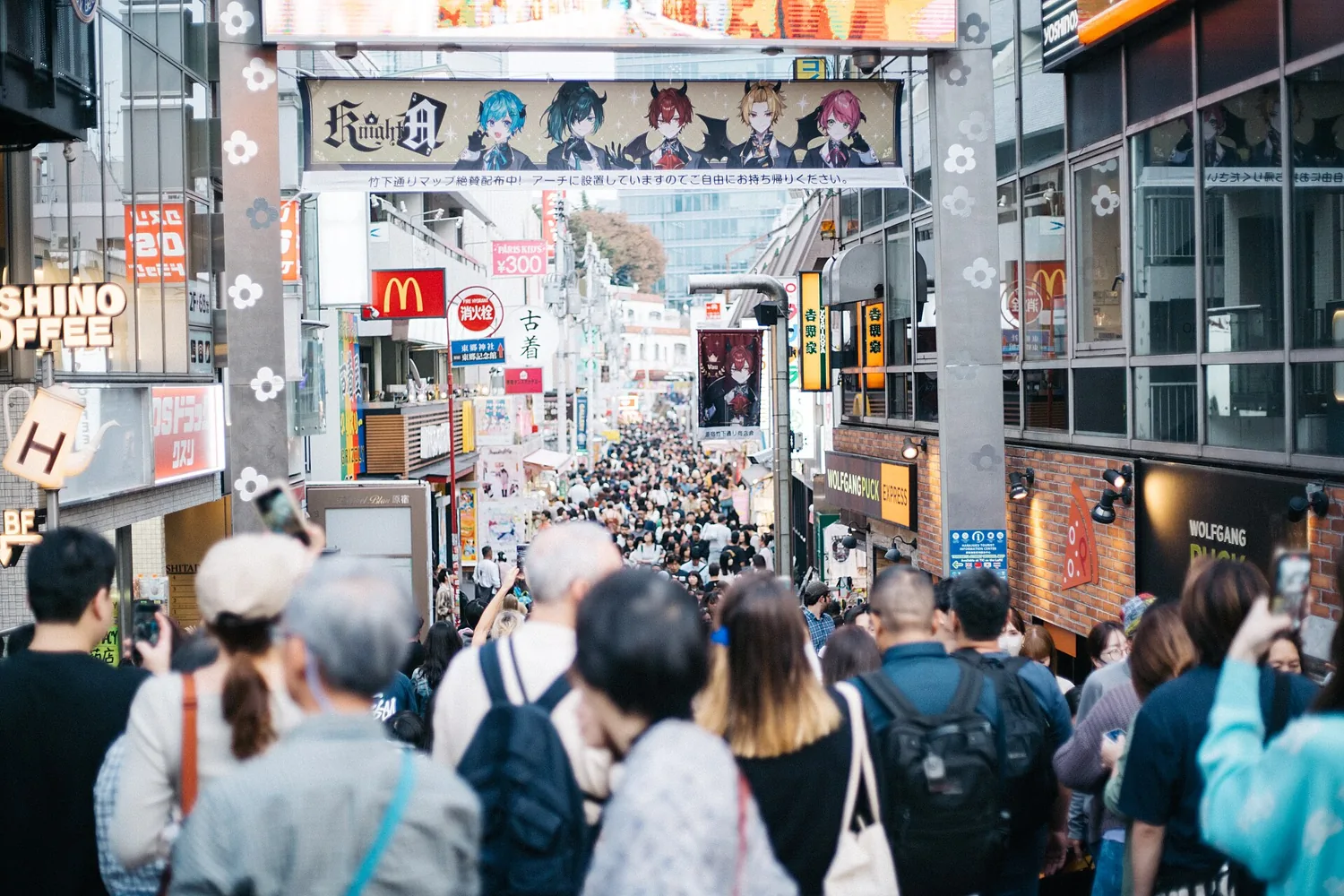A busy crowd of visitors walking down Takeshita Street in Harajuku, lined with colorful shop signs