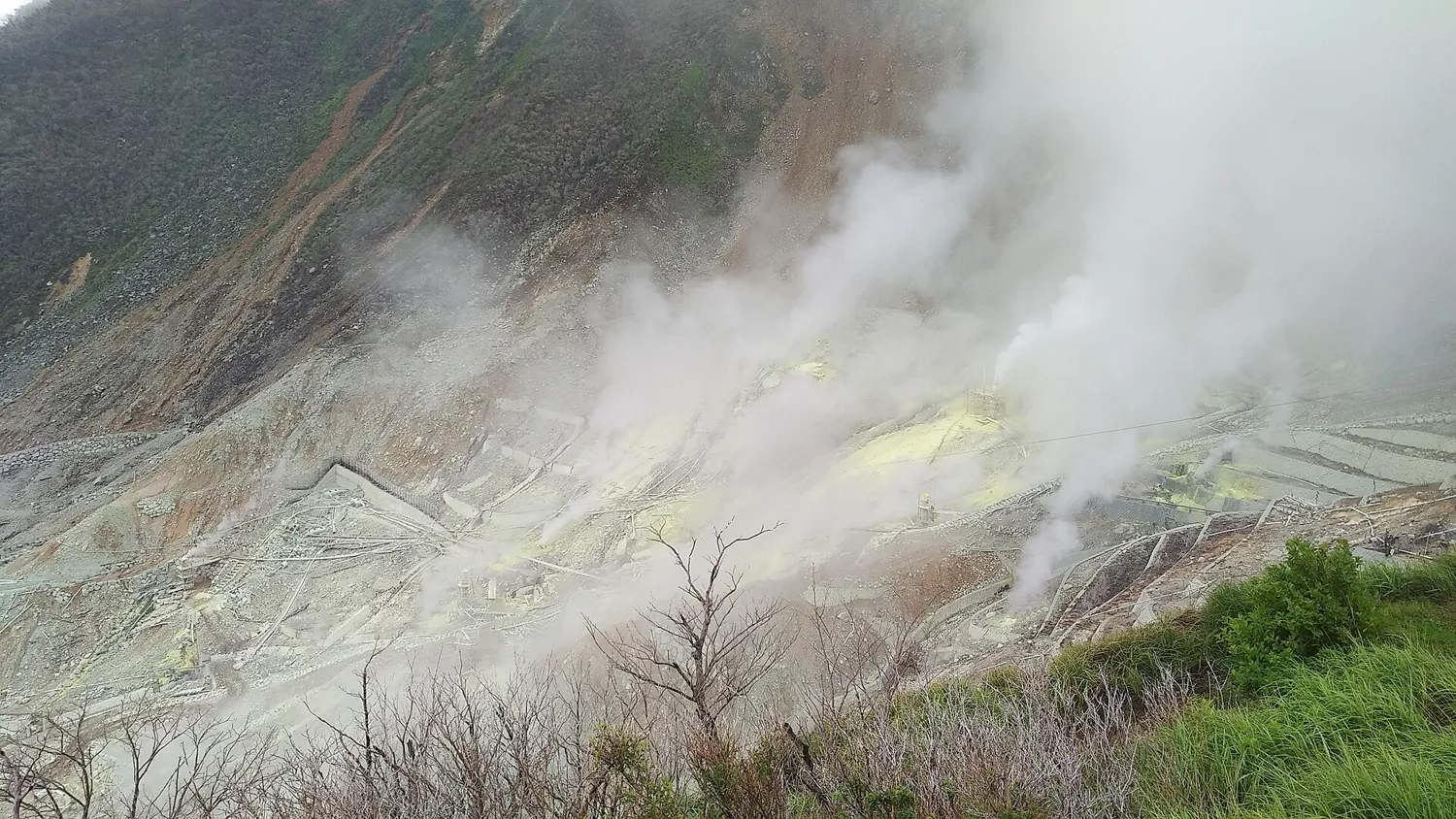 White steam pouring from vents on the grey slopes of Owakudani