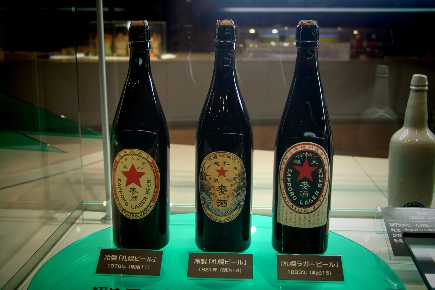 Three old dark beer bottles with red-star labels in a lit display case