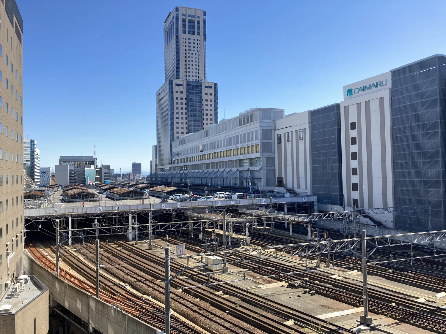 Sapporo Station seen from above, rows of tracks in front and the tall JR Tower rising behind