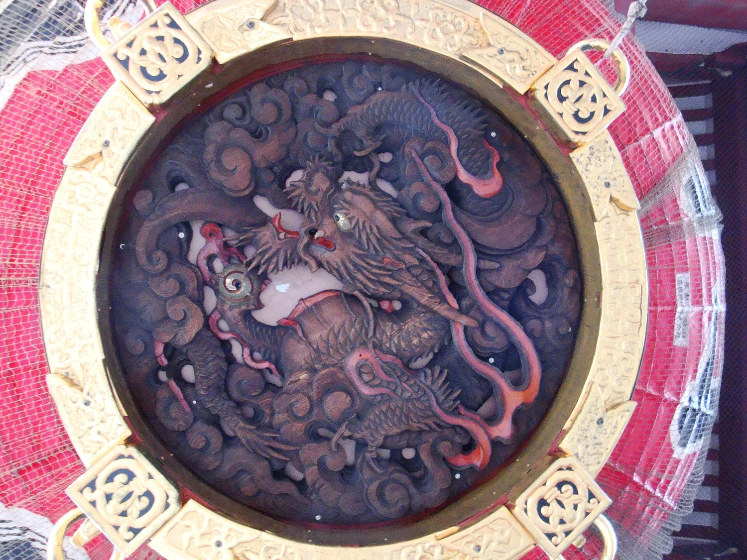 Carved wooden dragon on the underside of the giant red lantern at Kaminarimon, seen from directly below