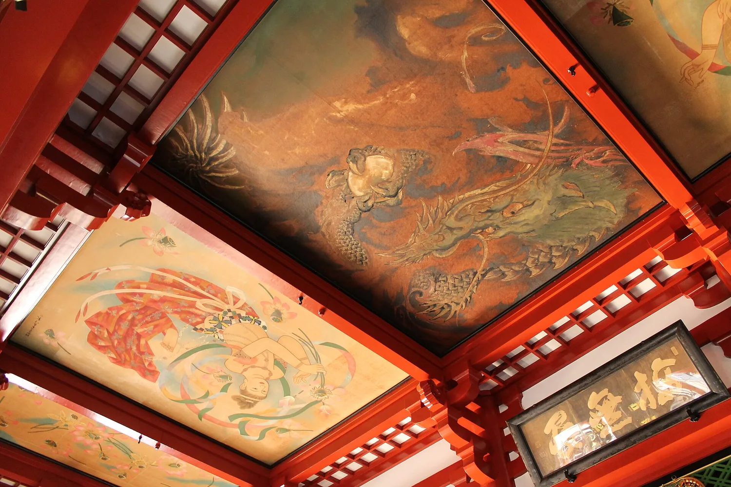 Ceiling of the main hall of Senso-ji with colorful paintings of heavenly beings and the dark dragon painting above red beams