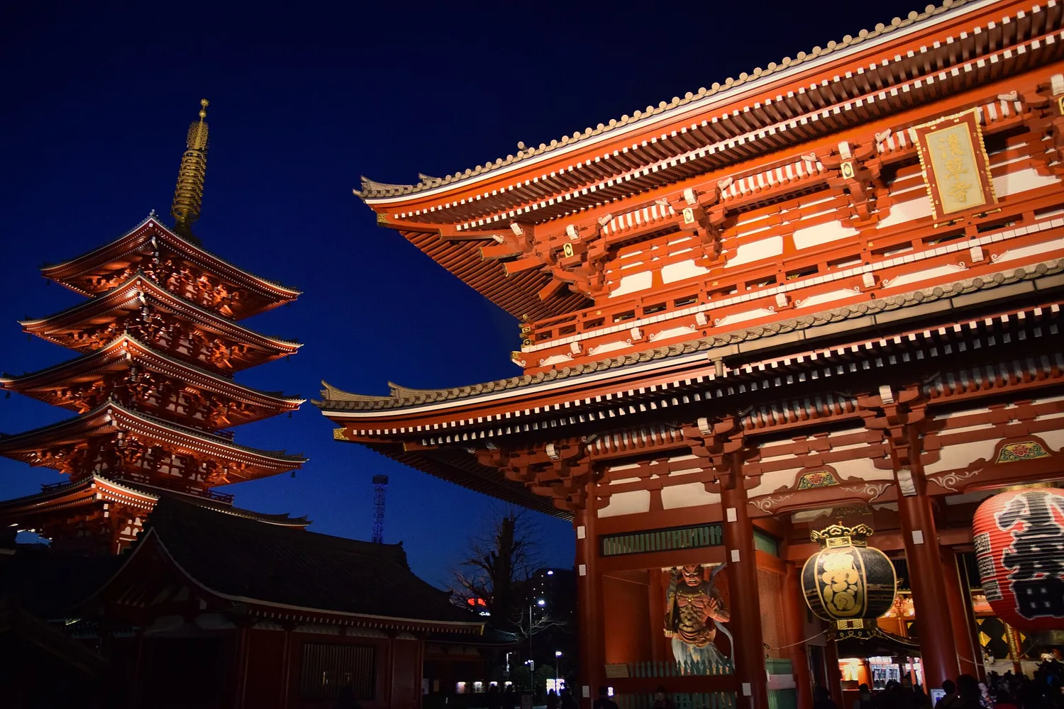 Senso-ji's five-story pagoda and Hozomon gate lit up at dusk against a deep blue sky