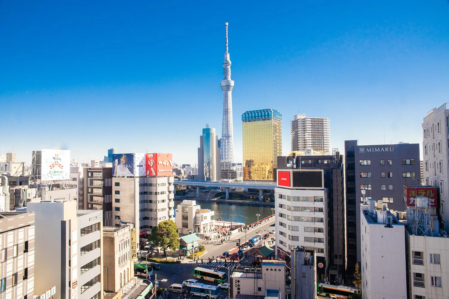 View of Tokyo Skytree rising above Asakusa and the Sumida River under a clear blue sky, from the Asakusa Culture Tourist Information Center