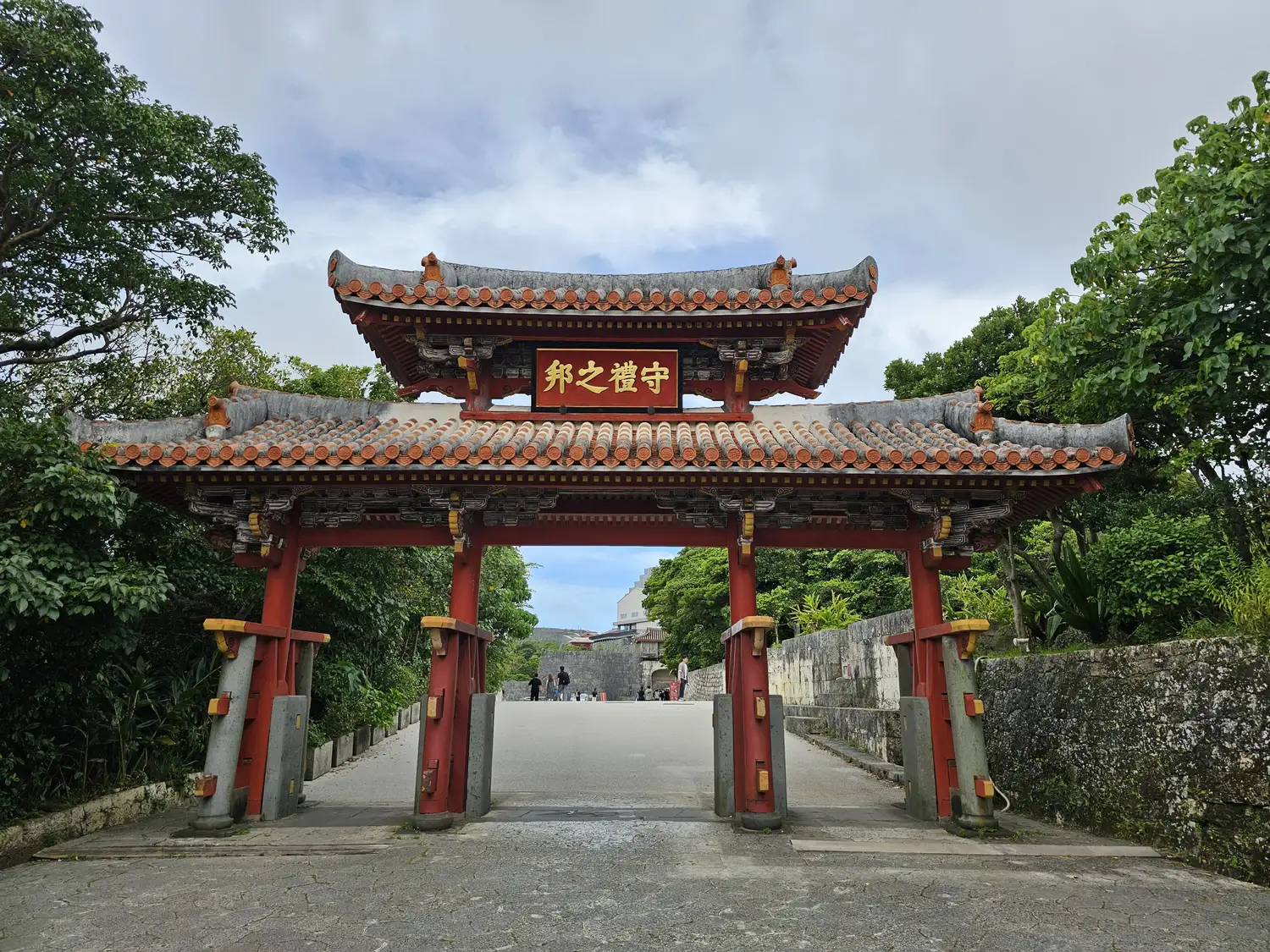 Shureimon gate, red pillars under a double tiled roof, with a plaque at the top