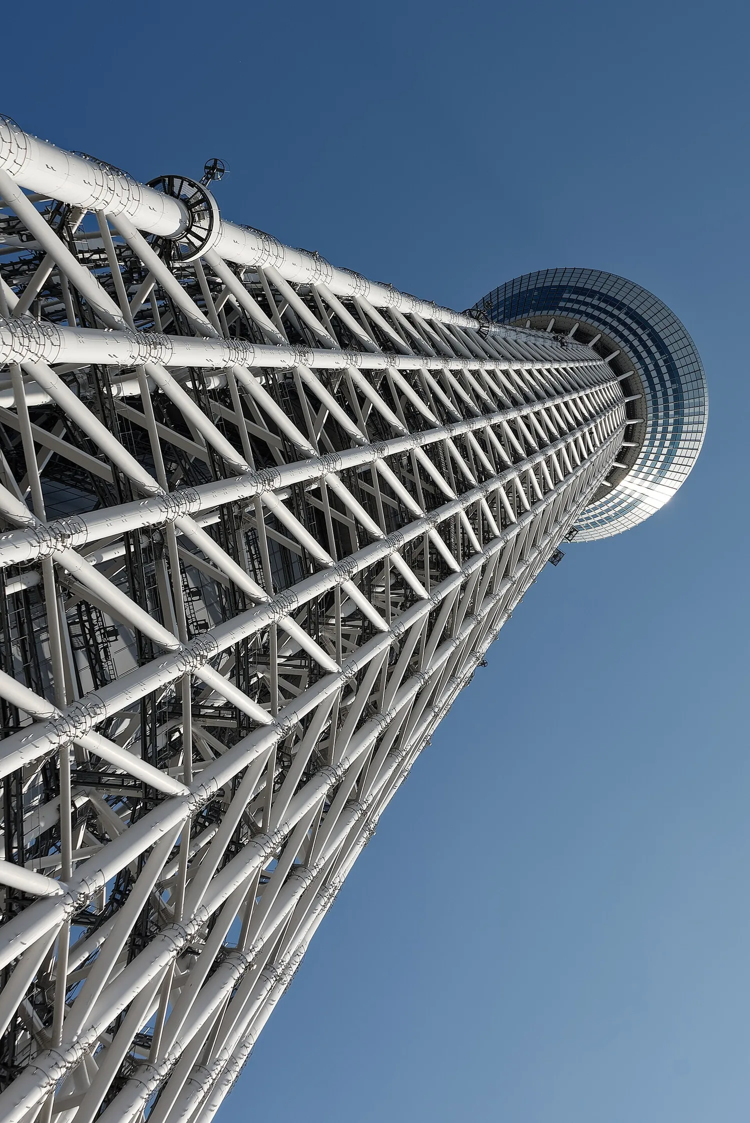 Looking straight up the white steel lattice of Tokyo Skytree against a blue sky