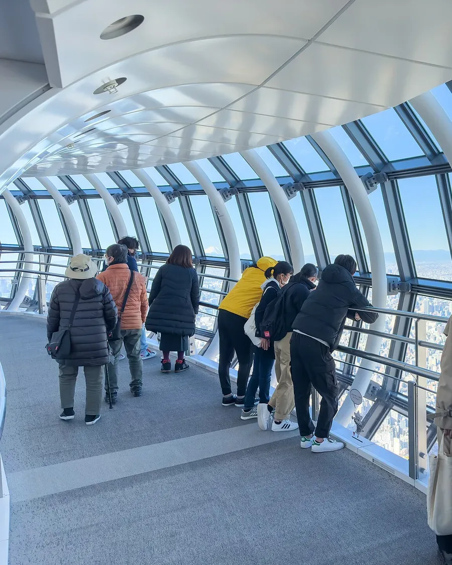 Visitors at the curved glass windows of the sloping Tembo Galleria corridor in Tokyo Skytree