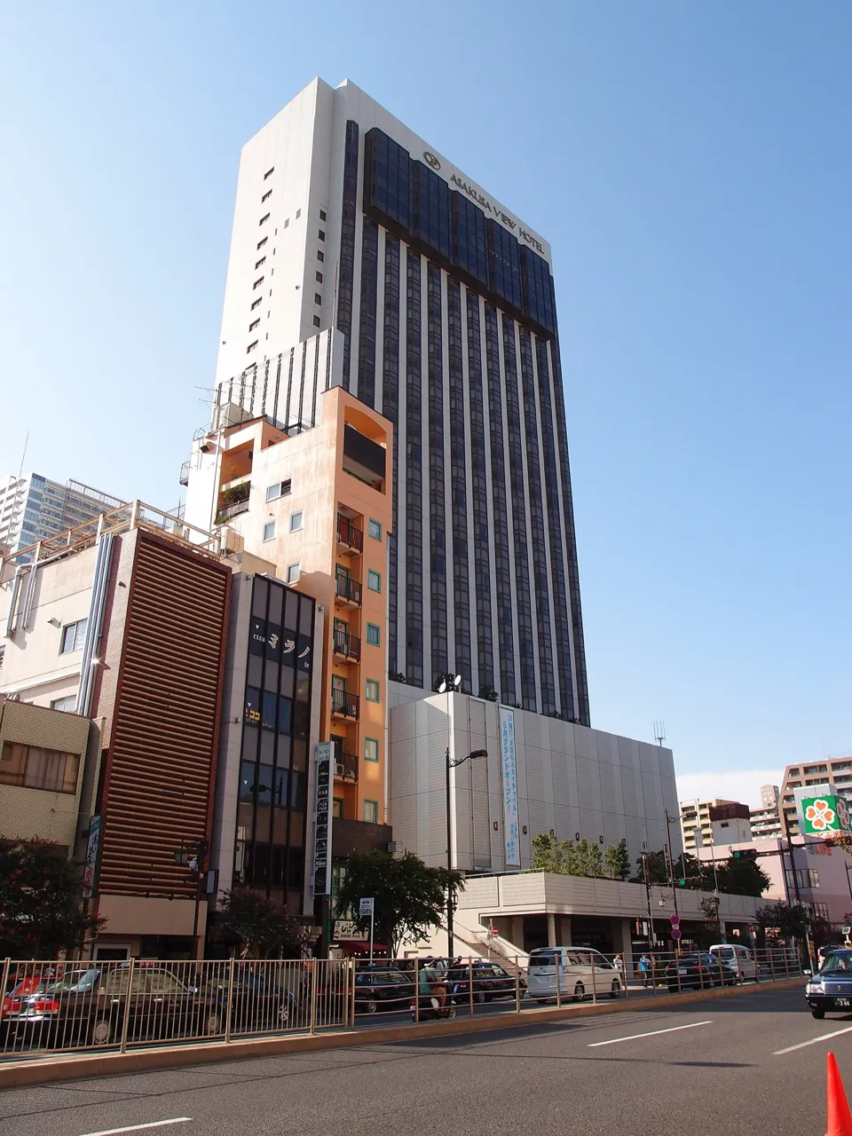 The tall tower of the Asakusa View Hotel, with its name near the top, rising behind a lower wing under a clear blue sky