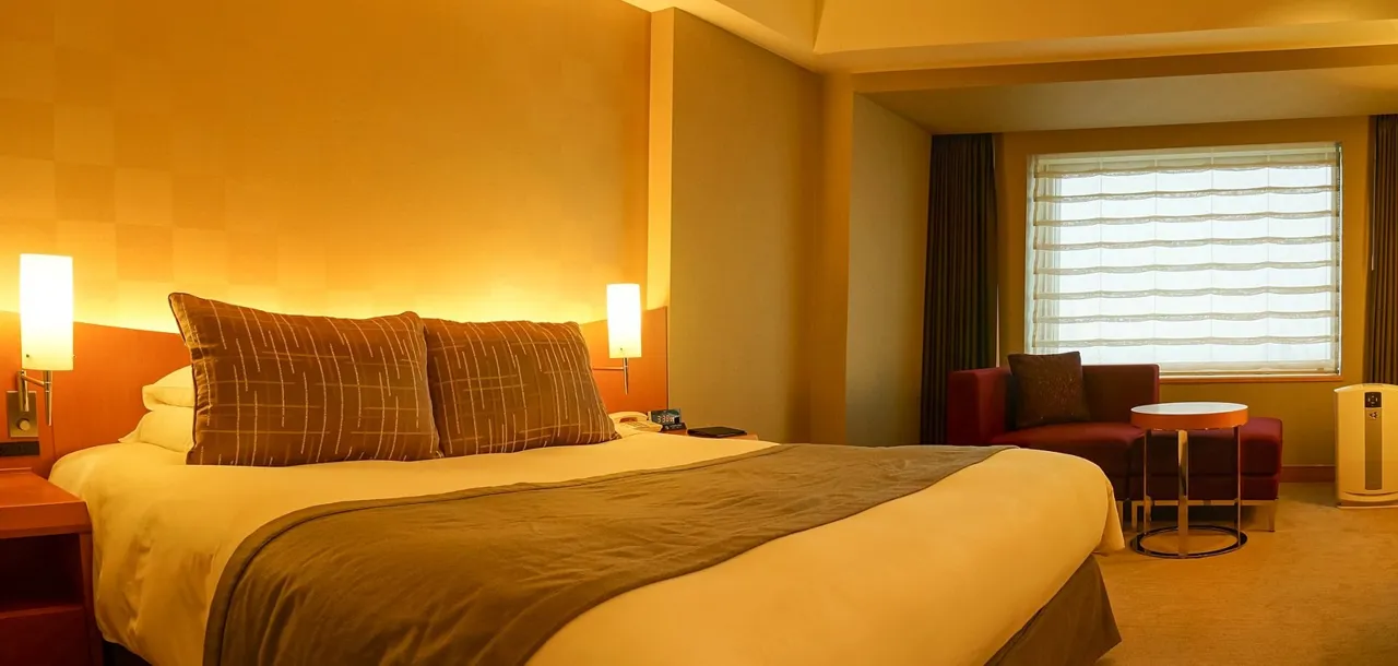 A Sky View Floor deluxe single room at the Cerulean Tower Tokyu Hotel, with a bed, warm lamps and a window with blinds