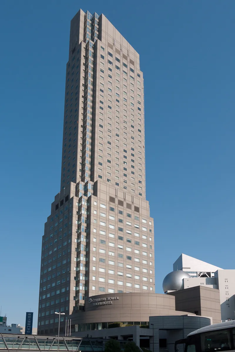Cerulean Tower in Shibuya, a tall pale tower with a curved top, standing against a blue sky