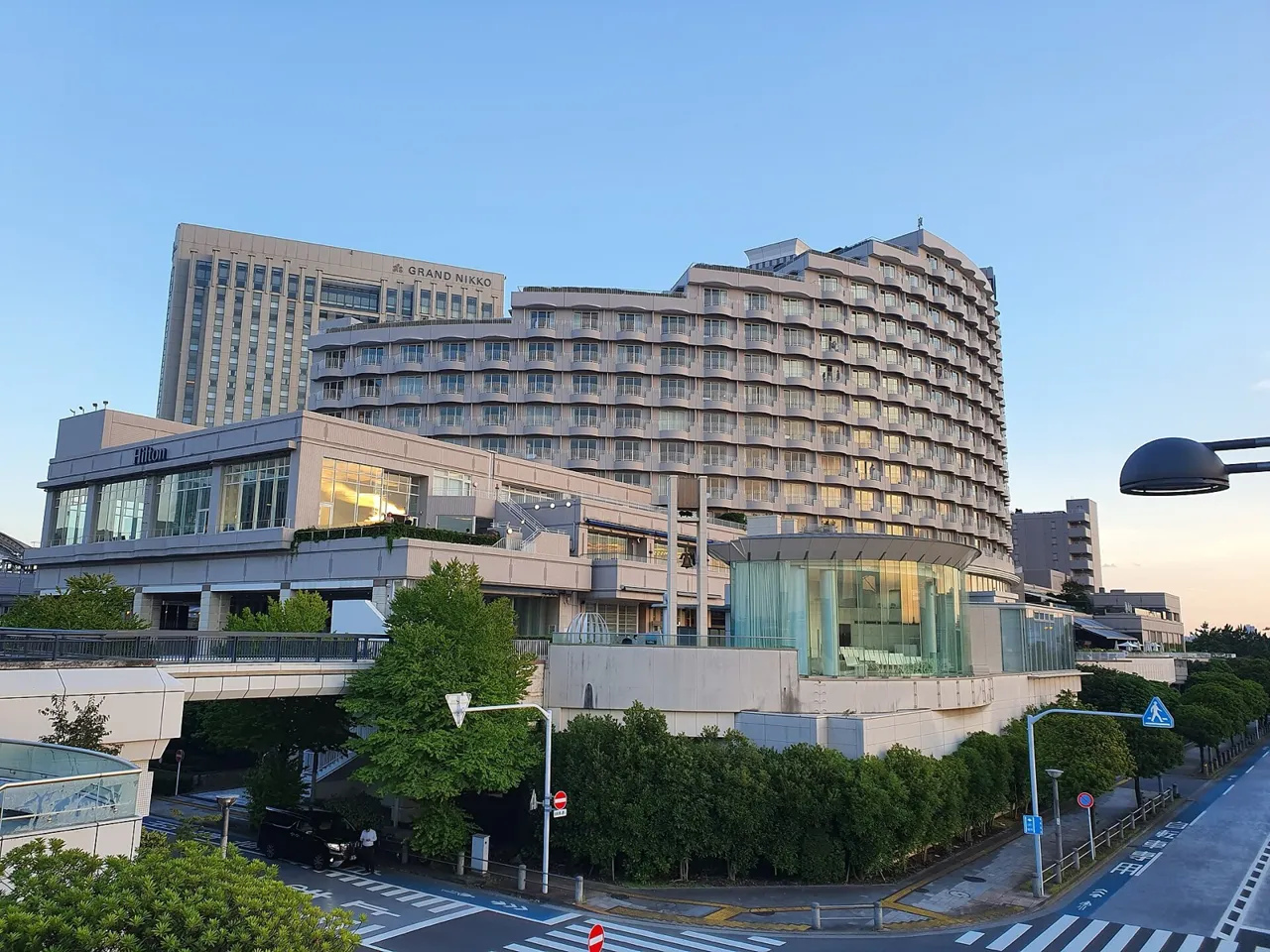 Hilton Tokyo Odaiba, its curved guest-room wing lined with balconies, above a lower wing in the late-day light