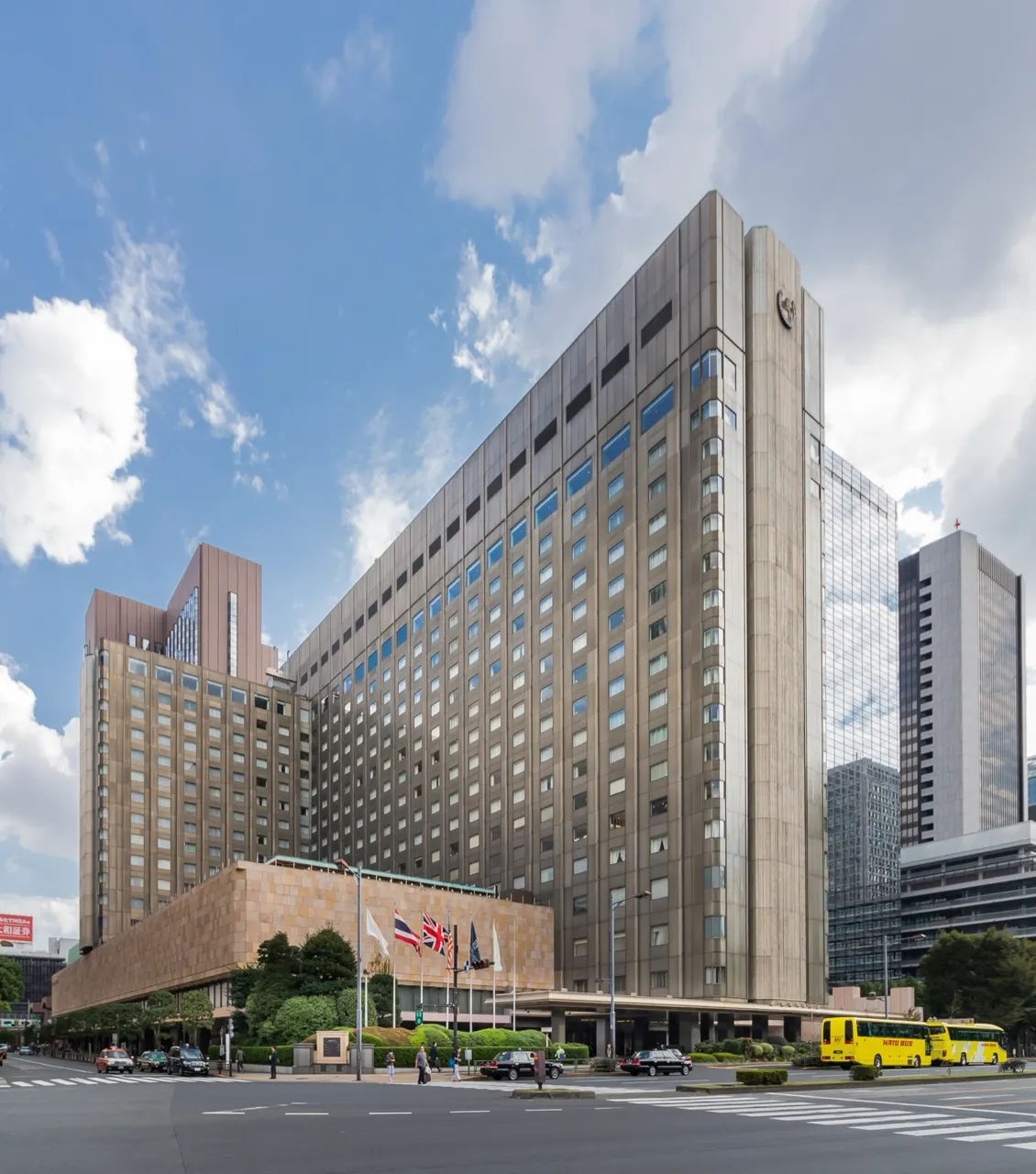 The main building of the Imperial Hotel, Tokyo, in Hibiya, a tall block above a stone-clad lower floor, under a blue sky
