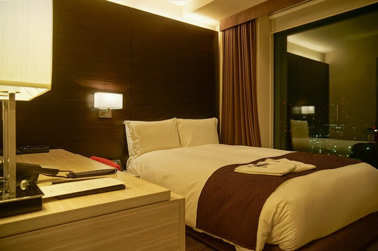 A guest room at Mitsui Garden Hotel Ginza Premier, with a double bed, a dark wood headboard and soft lamps