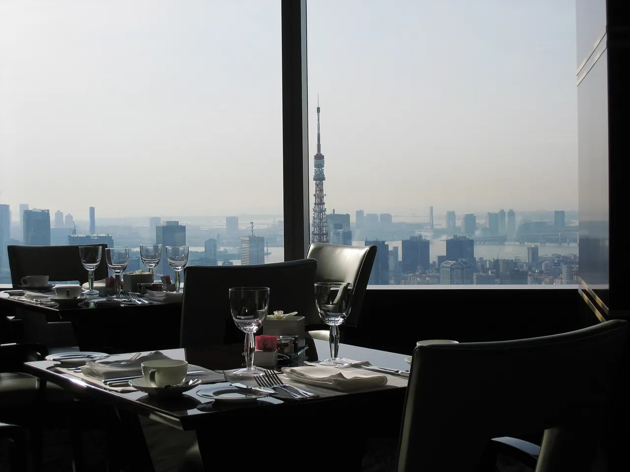 A window table in the 45th-floor restaurant of The Ritz-Carlton, Tokyo, set for breakfast, with the hazy city spread out below