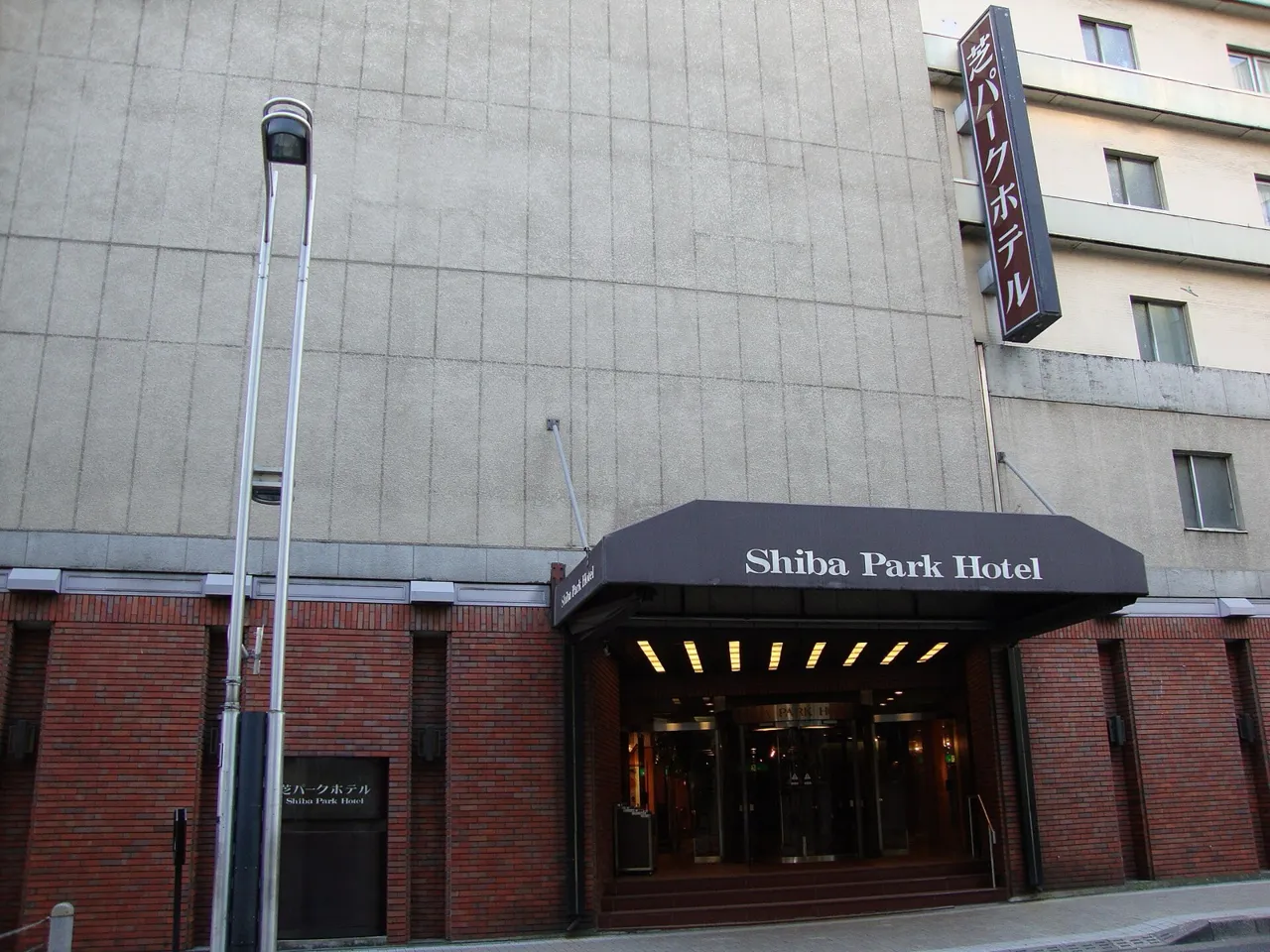 The entrance of the Shiba Park Hotel in the early evening: a brick lower wall, a black canopy with the hotel's name and a lit vertical sign