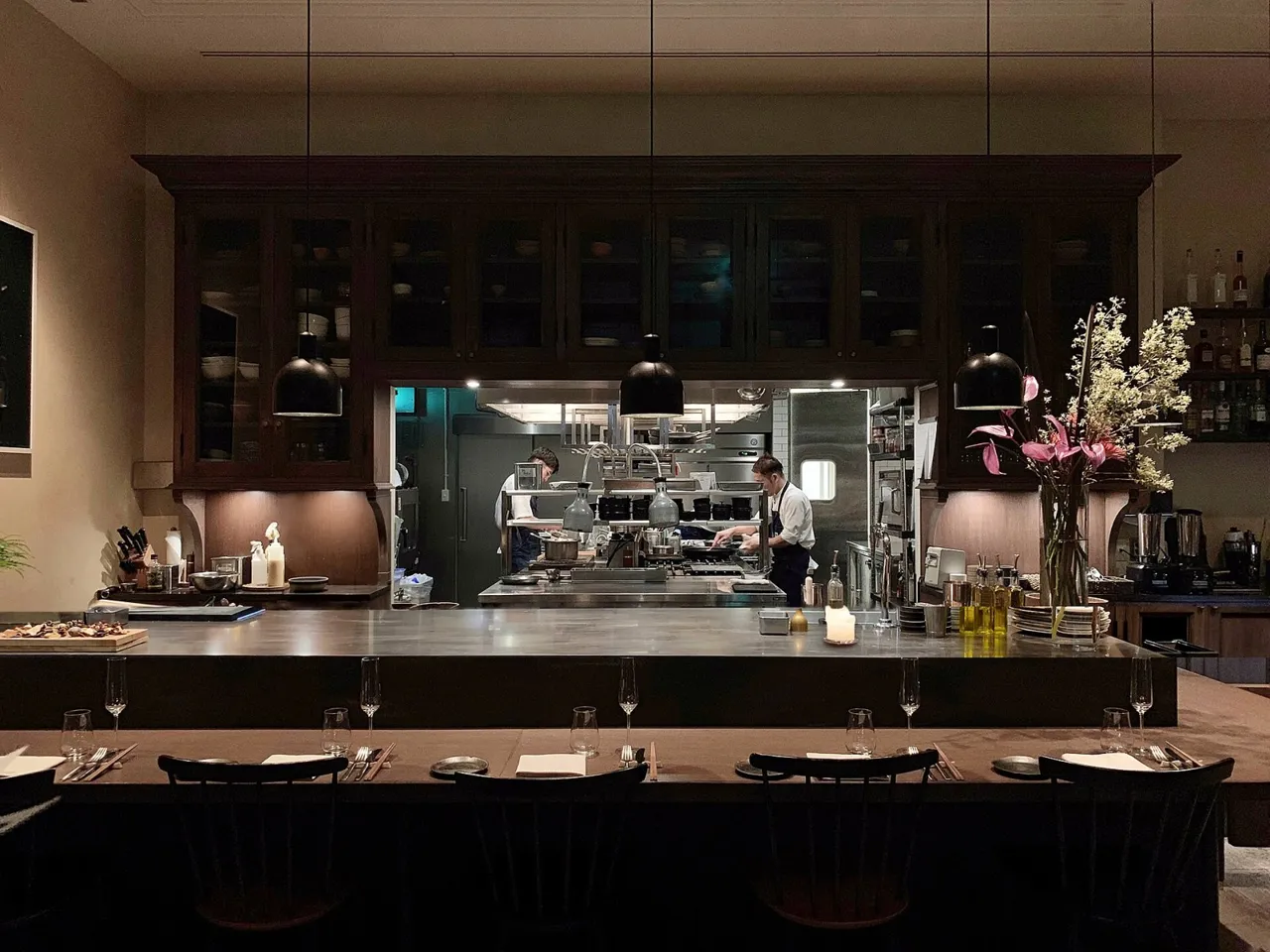 The restaurant at TRUNK(HOTEL) Cat Street: a dark counter with stools facing an open kitchen under pendant lights