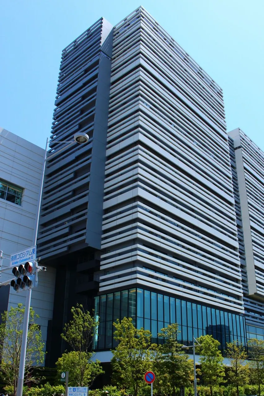 The dark grey, horizontally striped tower of Hotel Villa Fontaine Grand Tokyo Ariake against a blue sky